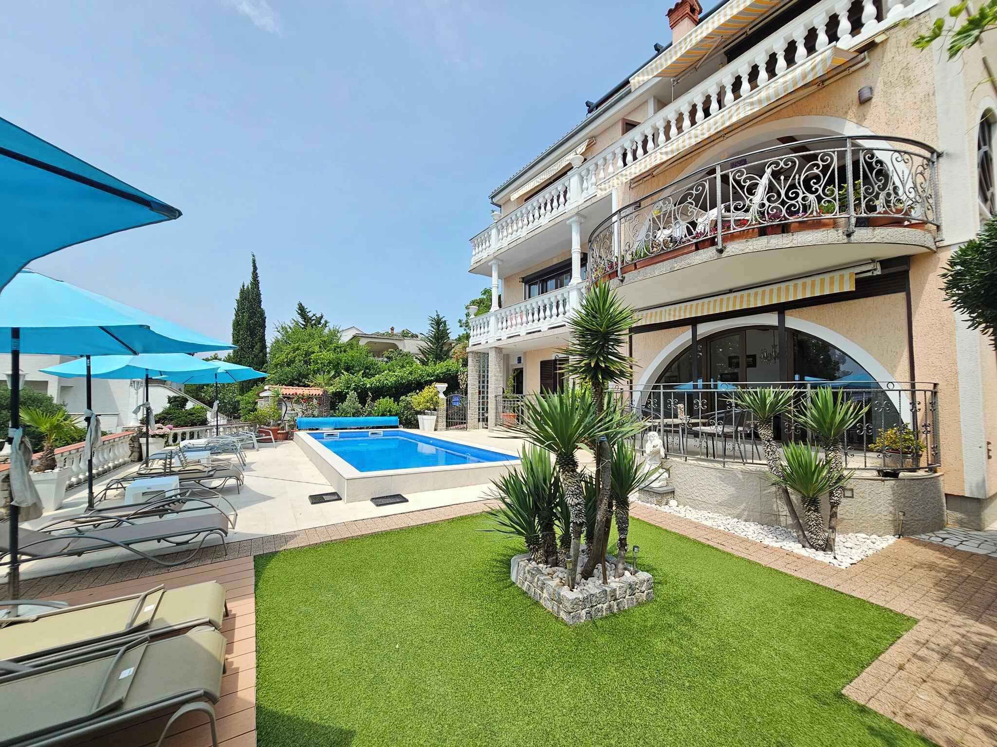 A pool area with lounge chairs, a small pool, and a well-maintained lawn.