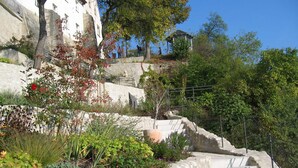Eine Steintreppe mit Geländern, umgeben von Pflanzen und einem Gebäude im Hintergrund.