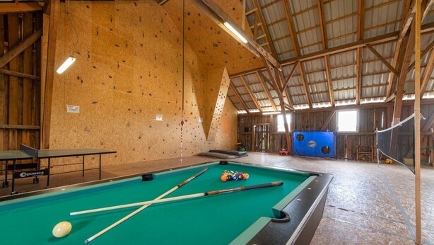 Un área recreativa interior con mesa de billar, pared de escalada y mesa de ping pong.