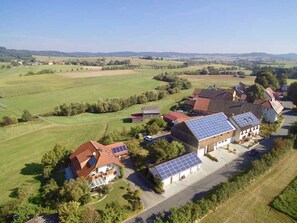 Un quartier résidentiel avec des maisons, dont certaines sont équipées de panneaux solaires, entouré de champs verdoyants et sous un ciel dégagé.