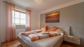 A bedroom with a large bed, a nightstand, a window with curtains, and a painting on the wall. - Apartment White - Apartment Zut (Ahorntal)