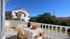 Une terrasse avec une table et des chaises, un pot de fleurs et une pastèque.