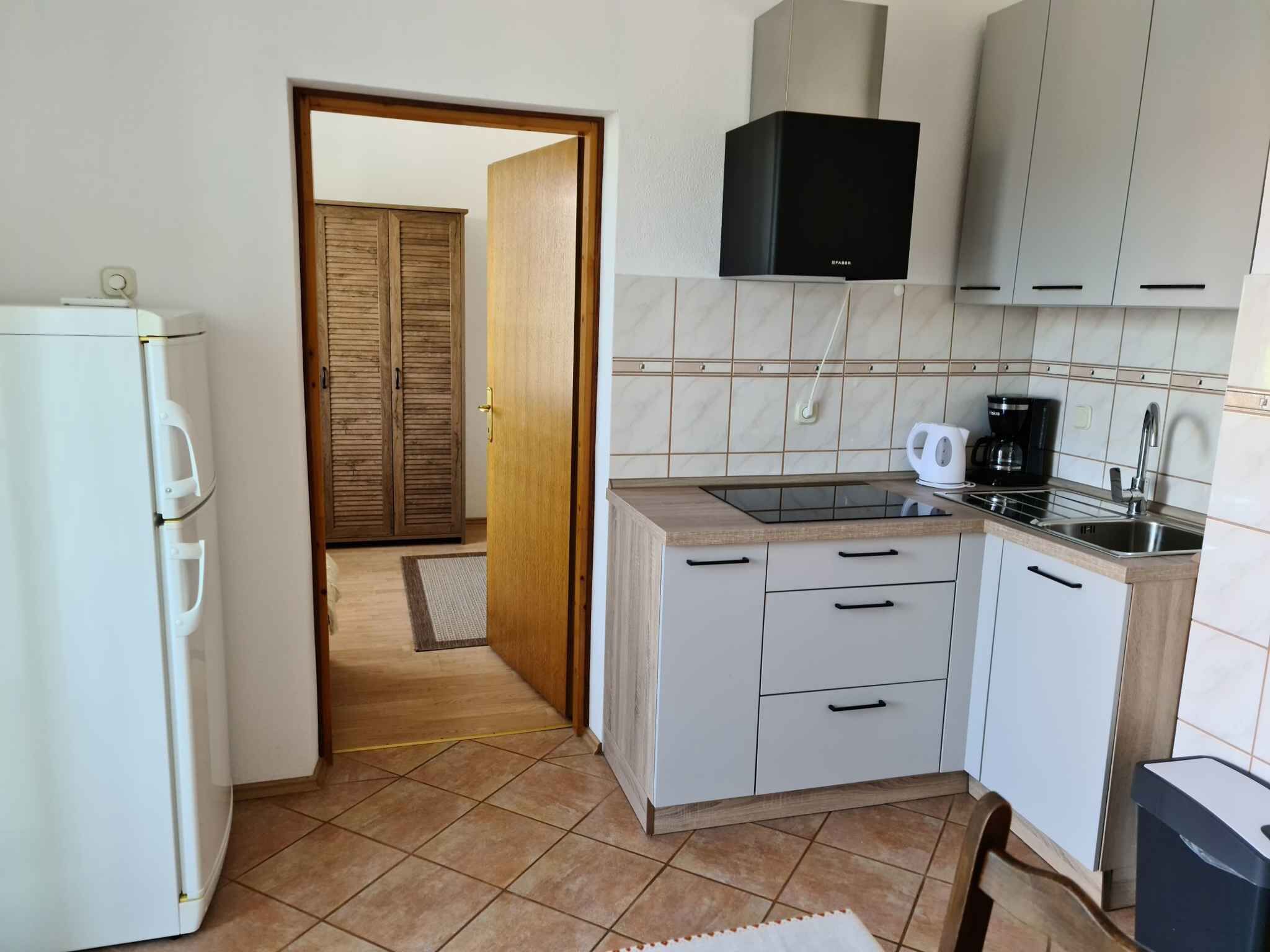 A compact kitchen with a refrigerator, a coffee maker, and cabinets.