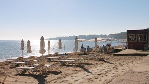 Une plage avec des chaises longues et des parasols, une tour de surveillance pour les sauveteurs, et une vue dégagée sur la mer.