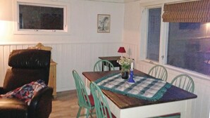 A dining area with a wooden table, green chairs, a red lamp, and a window with blinds. - Gorgeous home in Vågstranda with house sea view (Vågstranda)