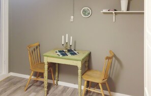 A small dining area with a table and two chairs, a candelabra with candles, a wall clock, and a shelf with a vase. - Gorgeous home in Vågstranda with house sea view (Vågstranda)