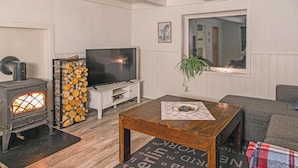 A cozy living room with a wood-burning stove, a television, and a comfortable seating area. - Gorgeous home in Vågstranda with house sea view (Vågstranda)
