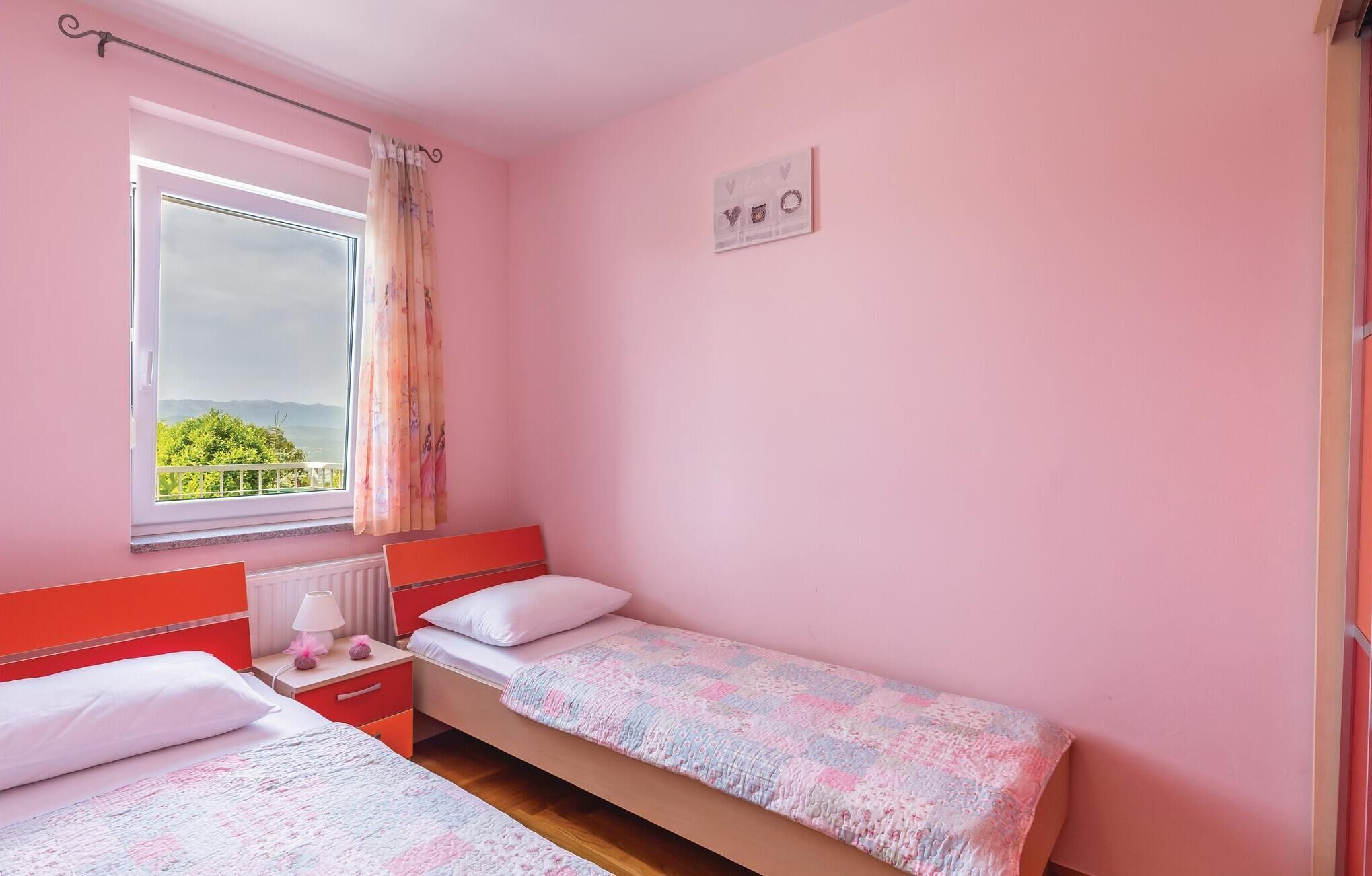 Un dormitorio con dos camas individuales, una ventana con vistas a la vegetación y un estante en la pared con adornos.