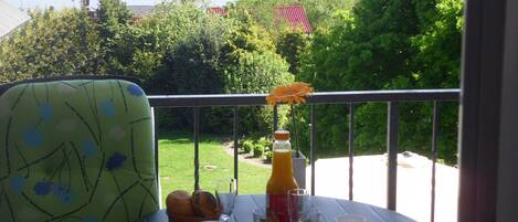 Una mesa con alimentos para el desayuno, una silla y vistas a árboles y agua.