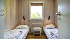 Een kleine kamer met twee bedden, een raam en een nachtkastje.