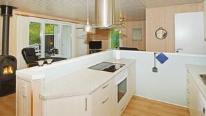 Een moderne keuken met een centraal eiland, een fornuis en een eetgedeelte met een stoel en tafel.