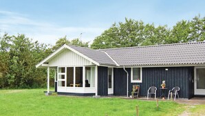 Een tweelaags gebouw met een overdekte veranda en een omheinde tuin.