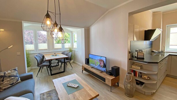 A modern living room with a dining area, a kitchen, and a TV. - Villa Störtebeker Whg. 08 - Villa Störtebeker Whg. 08 (Göhren)