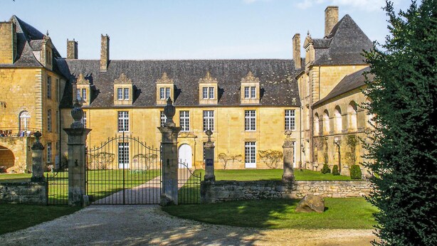 A historic building with a symmetrical facade, multiple windows, and a central entrance gate. - Beautiful home in St Amand de Coly (St Amand de Coly)