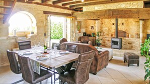 A rustic dining area with a stone wall, a fireplace, and a television. - Beautiful home in St Amand de Coly (St Amand de Coly)