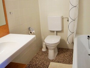 Ein Badezimmer mit weißem Waschbecken, WC und Badewanne.
