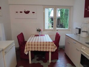 Eine kompakte Küche mit Esstisch, Stühlen, einer Kaffeemaschine und einem Fenster mit Blick auf Grünflächen.