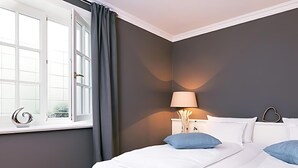 Une chambre d’hôtel avec un lit, une table de chevet, une lampe et une vue sur l’extérieur par une fenêtre.