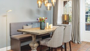 Un espace repas avec une table en bois, des bancs et des luminaires suspendus.