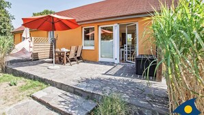 A house with a tiled roof, a patio with a table and chairs, and a red umbrella. - Blue hour, Germany (Heringsdorf)