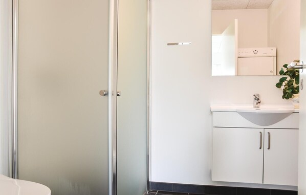 A modern bathroom with a white sink, mirror, and cabinets. - Beautiful home in Ringkøbing with WiFi (Ringkøbing)