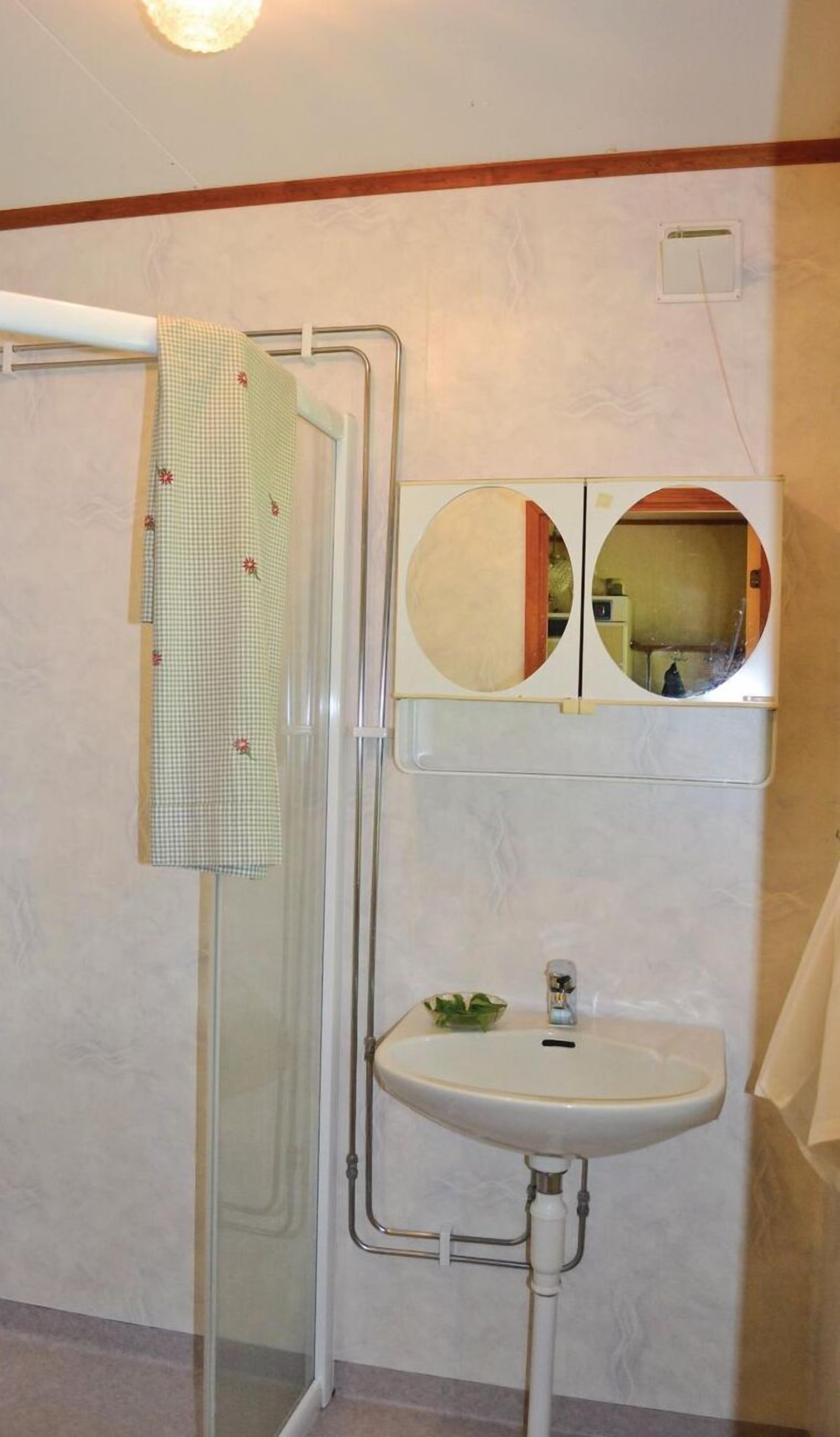 A bathroom with a shower, a sink, and a mirror.