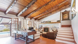 A spacious living area with a wooden ceiling, a fireplace, a dining table, and a sofa. - Nice home in Contursi Terme (SA) with sauna (Contursi Terme (SA))