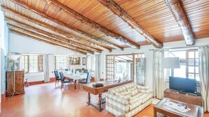 A spacious living area with a high wooden ceiling, a dining table with chairs, a sofa, a television, and a fireplace. - Nice home in Contursi Terme (SA) with sauna (Contursi Terme (SA))
