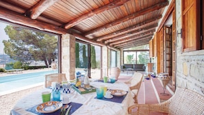 A covered outdoor dining area with a pool view, stone walls, and wicker furniture. - Nice home in Contursi Terme (SA) with sauna (Contursi Terme (SA))