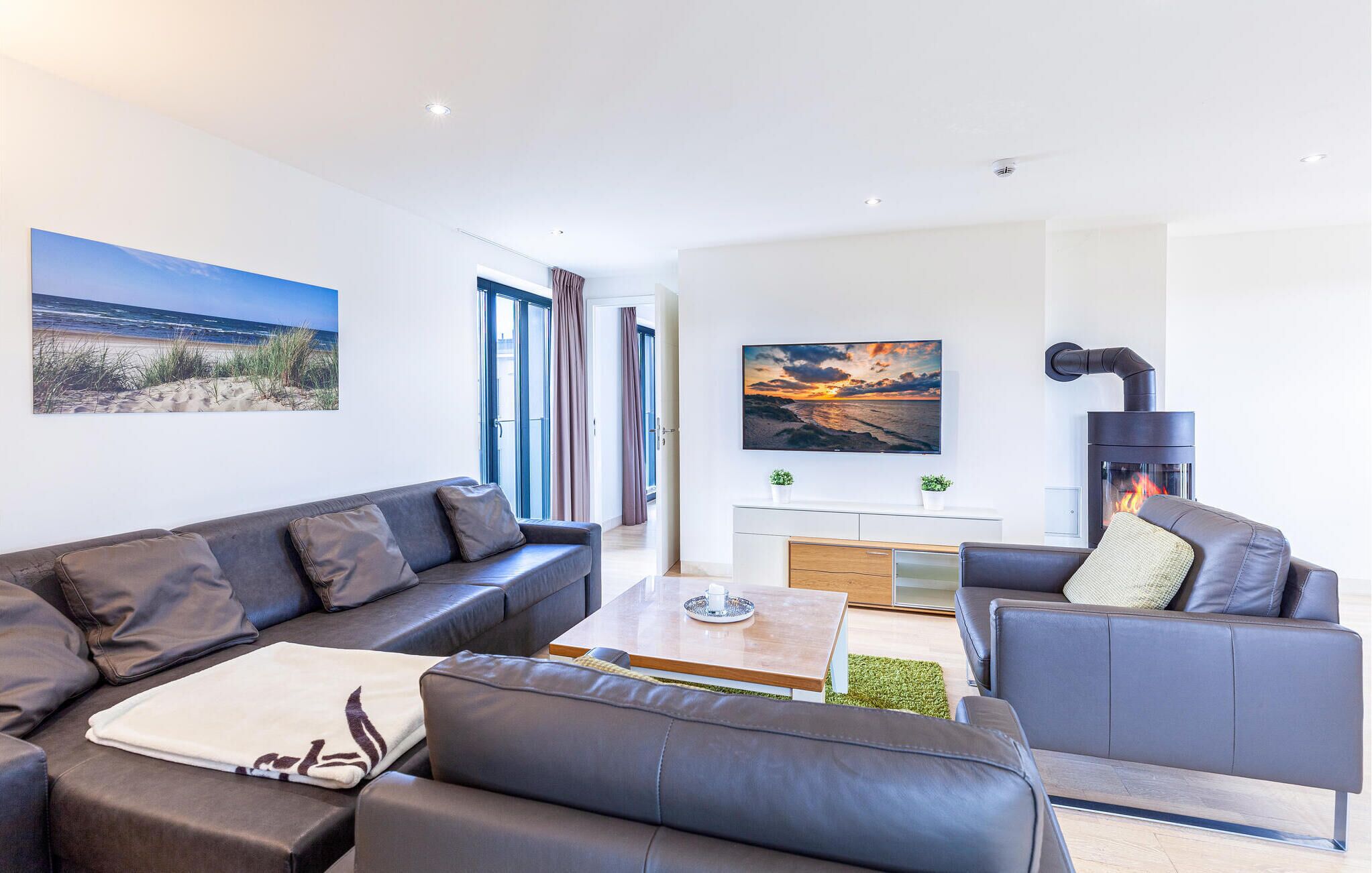 A modern living room with a sofa, armchairs, a coffee table, and a fireplace.