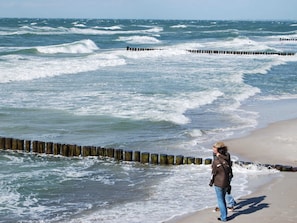 A beach with waves crashing onto wooden groynes.