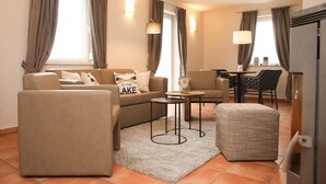 A modern living room with a sofa, armchair, ottoman, and coffee table. There is a dining area with a table and chairs. - Apartment with Jacuzzi (5) - Apartment near the beach (Nienhagen)