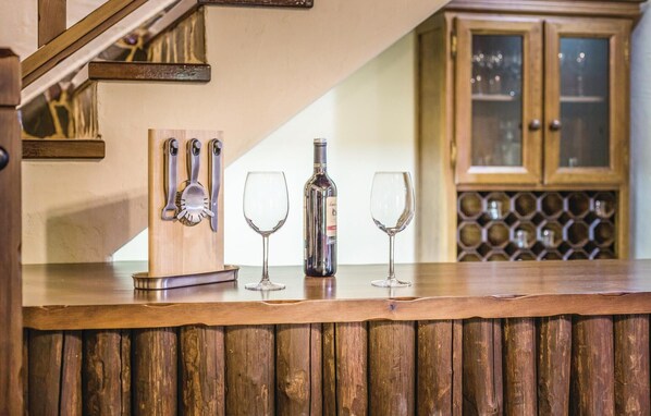 A bar area with a wooden counter, a wine bottle, and three wine glasses. - Stunning home in Montecorto, Málaga (Montecorto, Málaga)