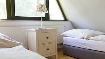 Een slaapkamer met een bed, nachtkastje met lamp, radiator en raam.
