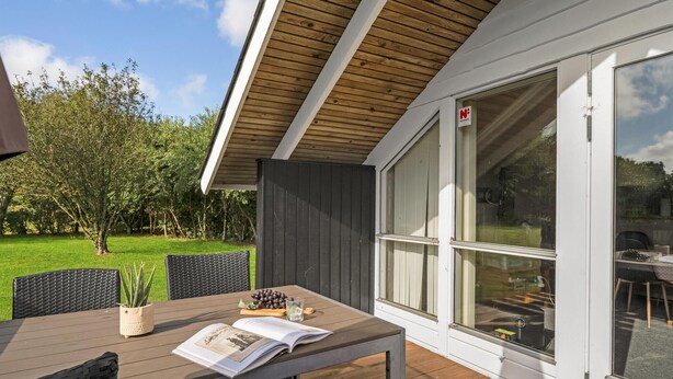 Een terras met een tafel, stoelen en een boek.
