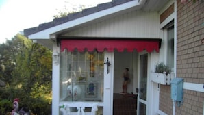 A house with a red awning, a white bench, and a brick exterior. - 1-room apartment 1, 30 m² - Graf Luckner Hüs (Scharbeutz)