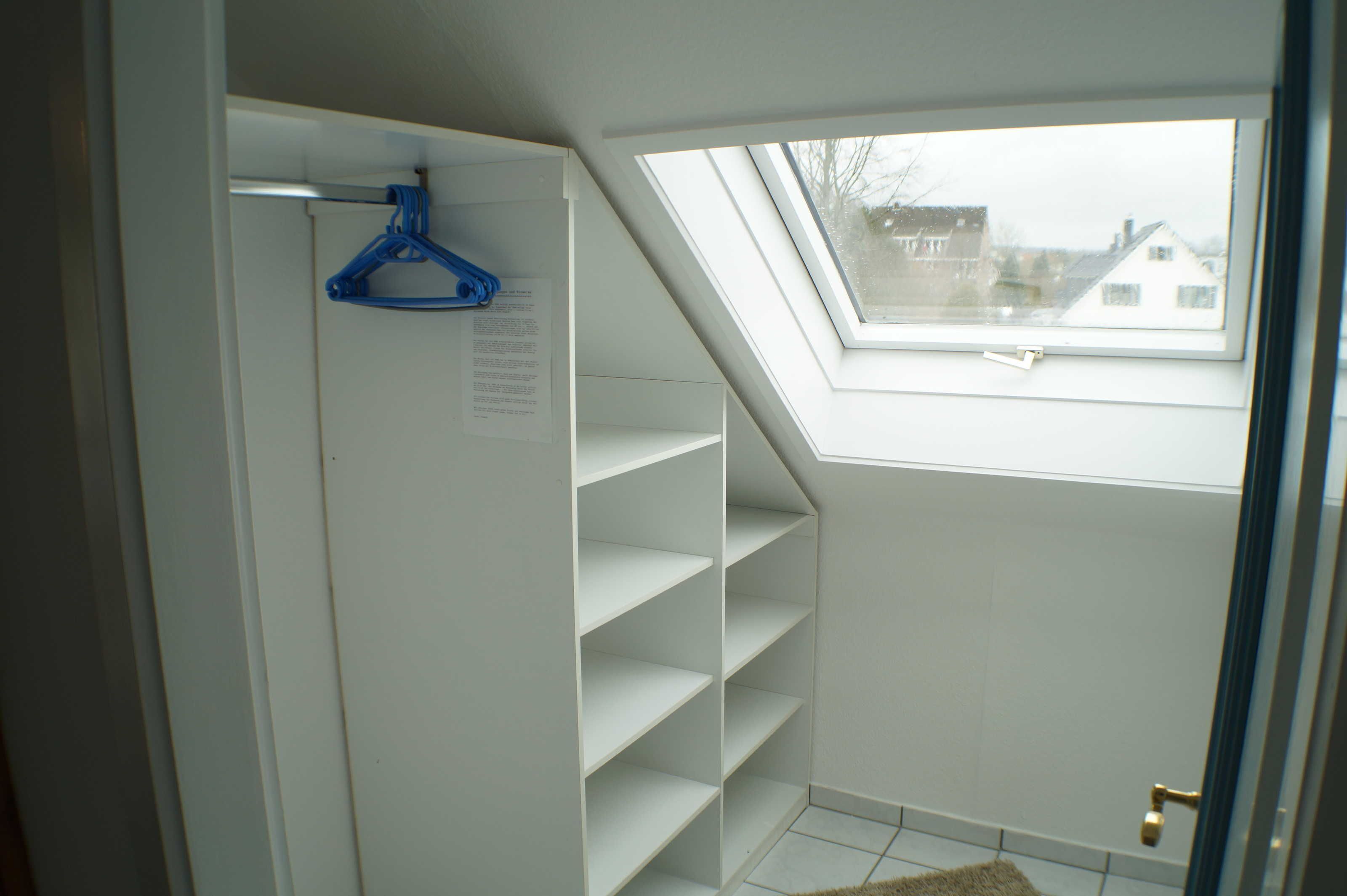 A room with a skylight, white walls, and a hanging blue hanger.