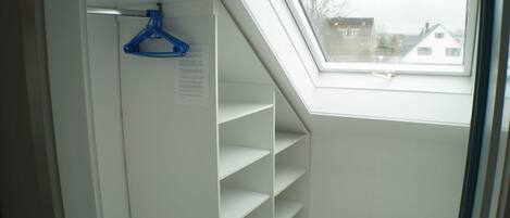 A room with a skylight, white walls, and a hanging blue hanger.