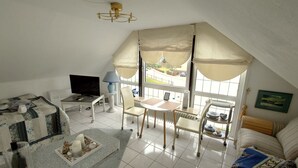 A cozy, well-lit room with a TV, a small dining table, and a sofa. - 1-room apartment 1, 30 m² - Graf Luckner Hüs (Scharbeutz)