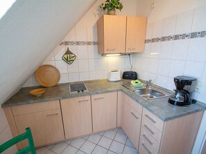 A compact kitchen with a built-in stove, a coffee maker, and a toaster. - Meadow ground 18 Whg. WiGr-18 - meadow ground 18 (Kühlungsborn)