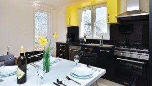 A modern kitchen with black cabinets, a stainless steel stove, and a yellow accent wall. - Amazing home in Lecevica (Lecevica)