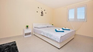 A bedroom with a bed, a bedside table with a plant, a window with sheer curtains, and wall art of butterflies. - Amazing home in Lecevica (Lecevica)