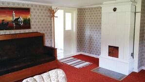 Un salon avec un canapé en bois foncé, un tapis à motifs, une cheminée et un tableau accroché au mur.