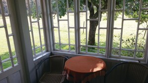 Une pièce dotée d’une grande fenêtre, d’une table ronde et de deux chaises en osier.