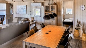 Een gezellig chaletinterieur met een houten eettafel, een bank en een bed.