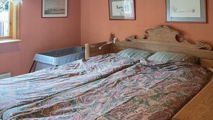Quarto com uma cama, um berço e três quadros na parede.