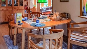Uma mesa de jantar de madeira com cadeiras, uma caixa de Stantill Naturelle e uma cesta de pão.