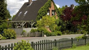 A house with a sloped roof, a wooden deck, and a fenced yard. - Bebensee, DZ DU / WC - Bebensee, Edda DZ (Neustadt in Holstein)