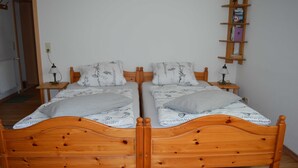 A double wooden bed with two nightstands, each with a lamp, in a room with a wooden floor and a white wall. - Bebensee, DZ DU / WC - Bebensee, Edda DZ (Neustadt in Holstein)