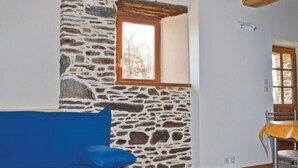 A room with a stone wall, a wooden ceiling, a blue sofa, and a wooden table. - Amazing home in Minihy Treguier (Minihy Treguier)